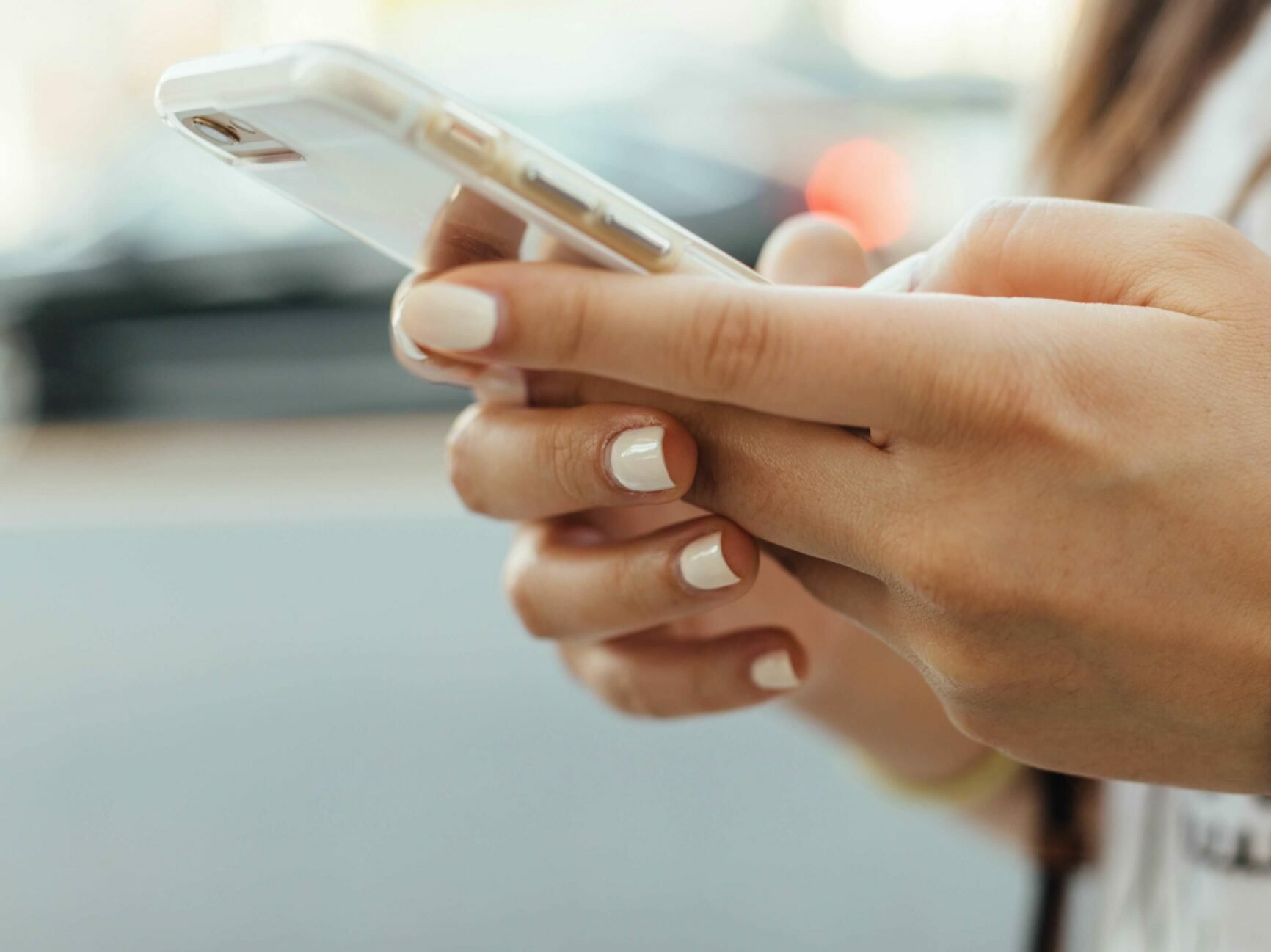 Nahaufnahme von gefalteten Händen, die ein Smartphone in transparenter Hülle halten