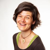 Lächelnde Frau mit kurzem dunklen Haar, grüner Bluse und einer Halskette