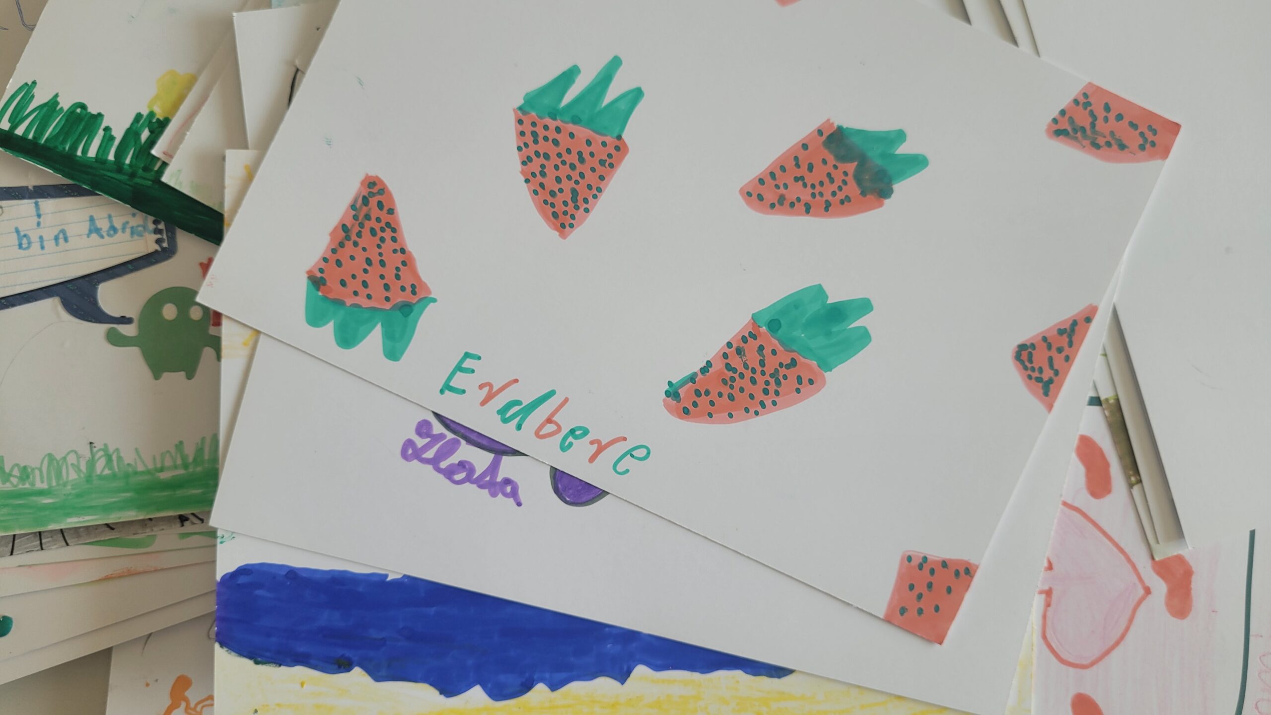 Stapel von Kinderzeichnungen mit Erdbeeren, Schriftzügen und Herzen