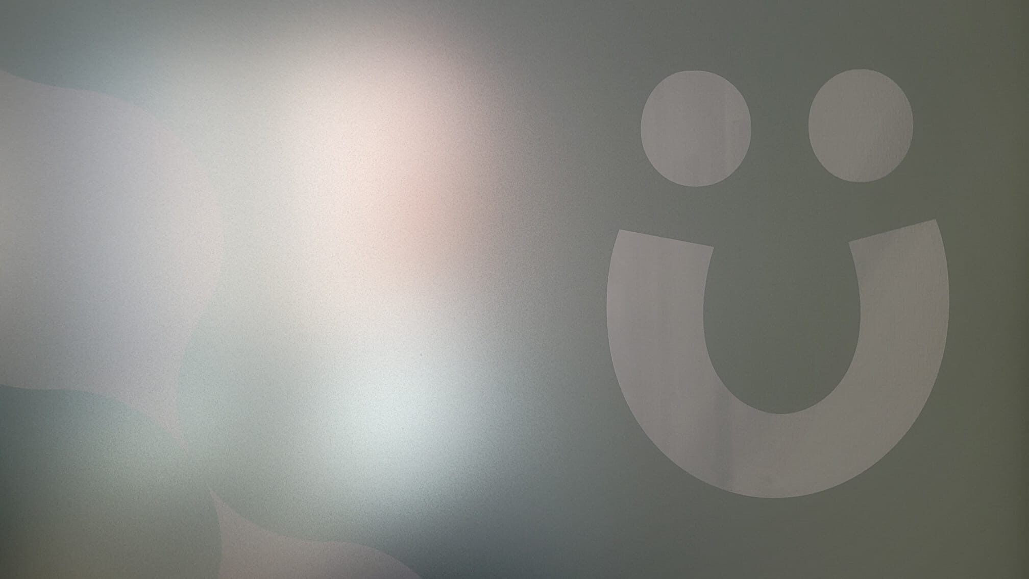 Weißes Smiley aus zwei Kreisen als Augen und einem Bogen als Mund auf grauer Fläche