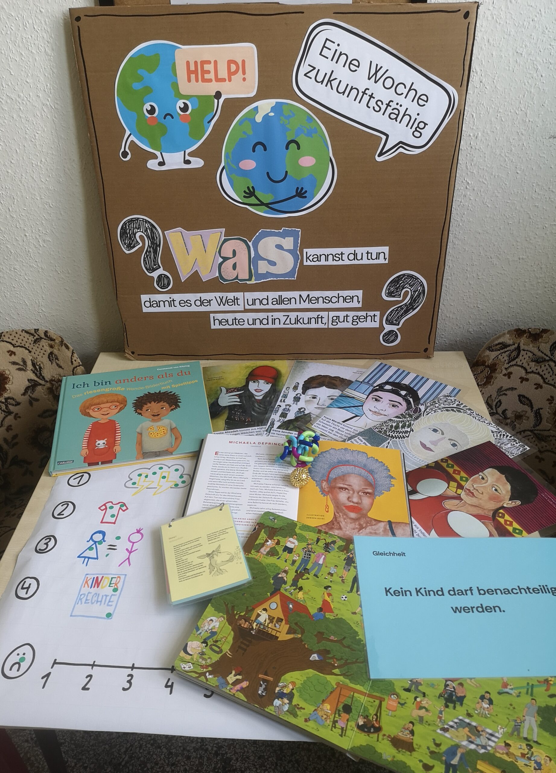 Selbst gestaltetes Plakat „Eine Woche zukunftsfähig“ mit der Frage „Was kannst du tun, damit es der Welt und allen Menschen heute und in Zukunft gut geht?“, davor ausgelegte Bücher und Materialien zu Kinderrechten und Vielfalt