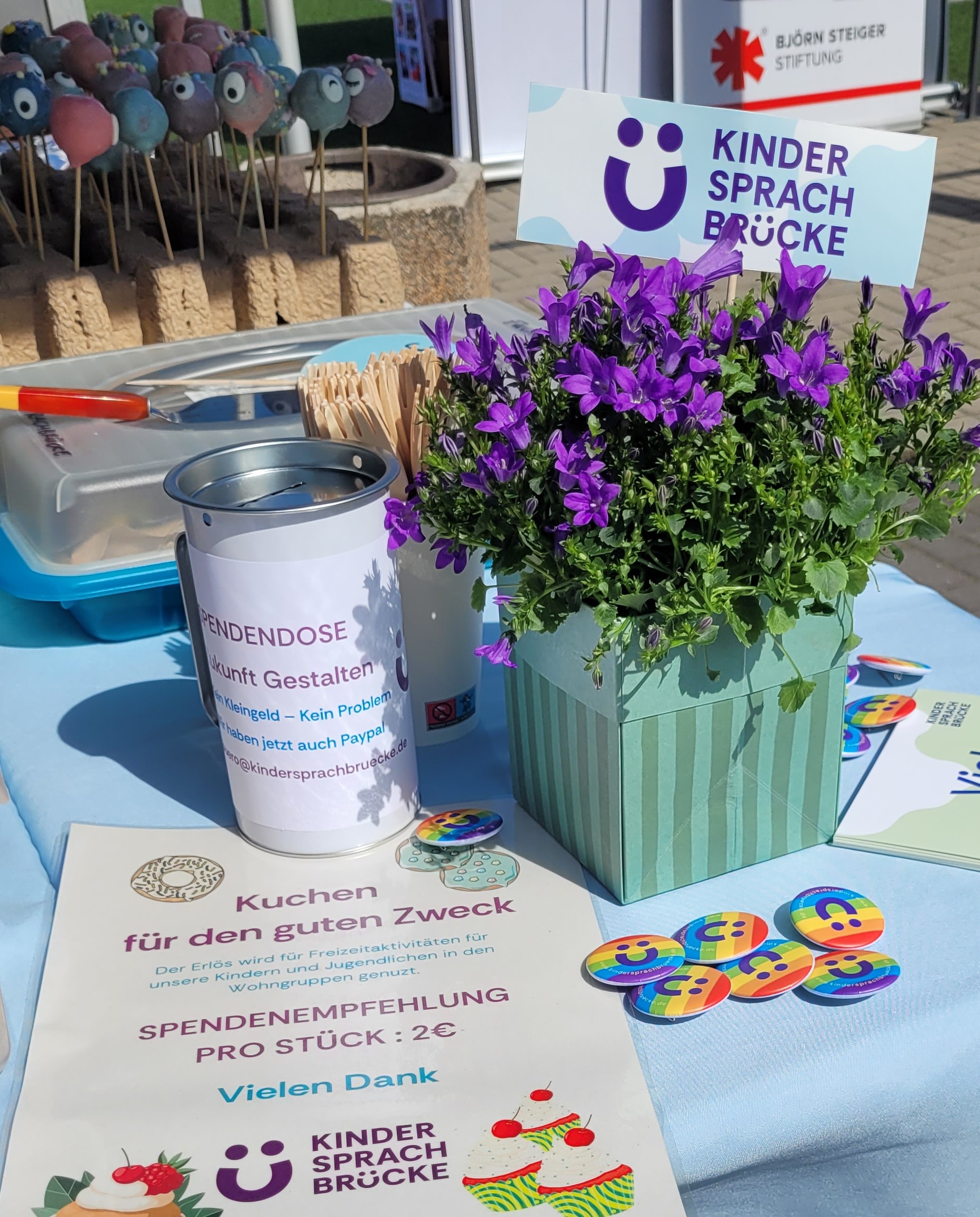 Stand der Kinder Sprach Brücke: Spendenaktion Kuchen für den guten Zweck, 2 € pro Stück, Spendendose und Infomaterial